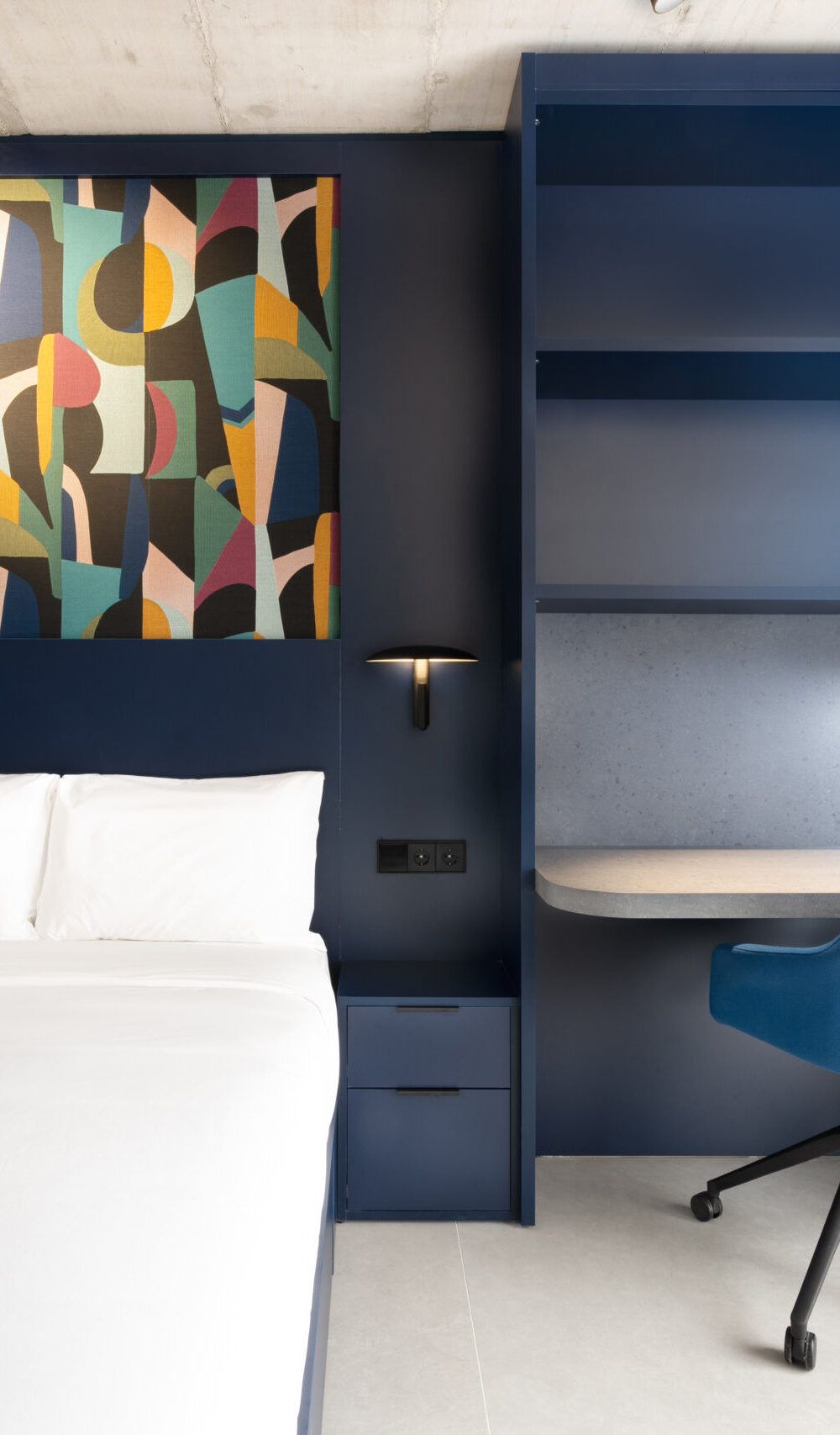 Blue built-in bedroom furniture with bed, abstract artwork, desk and blue chair