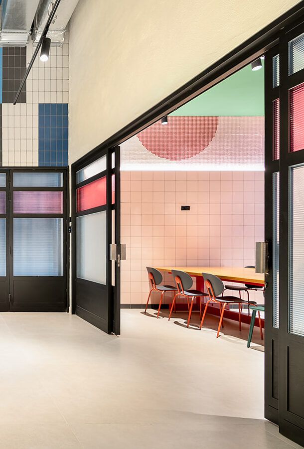 Open doors reveal a colourful room with a long table and chairs.