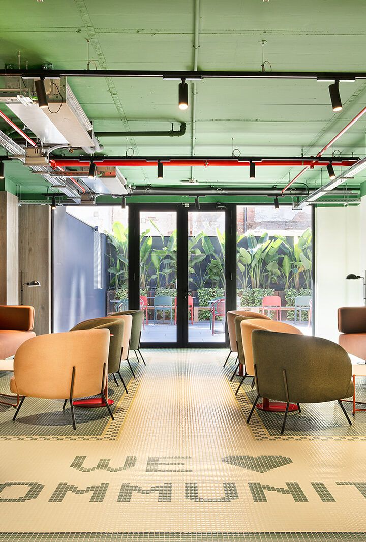 Sala de estar moderna para oficina con sillones de colores, puertas de cristal y un suelo con estampado.
