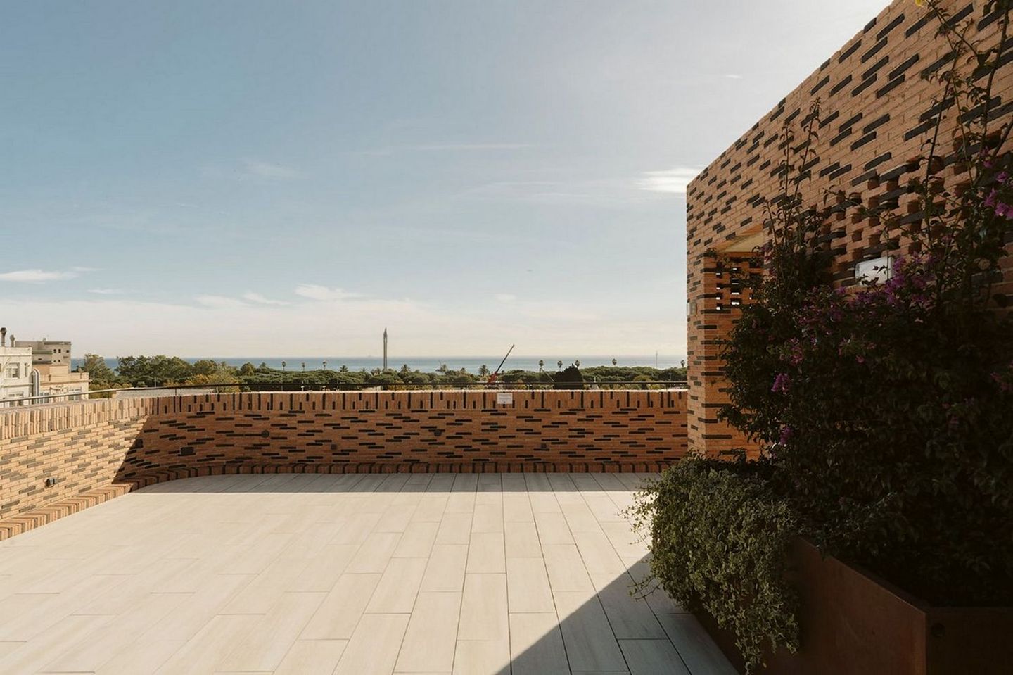 Rooftop terrace with brick walls, tiled floor and plants overlooking the sea.