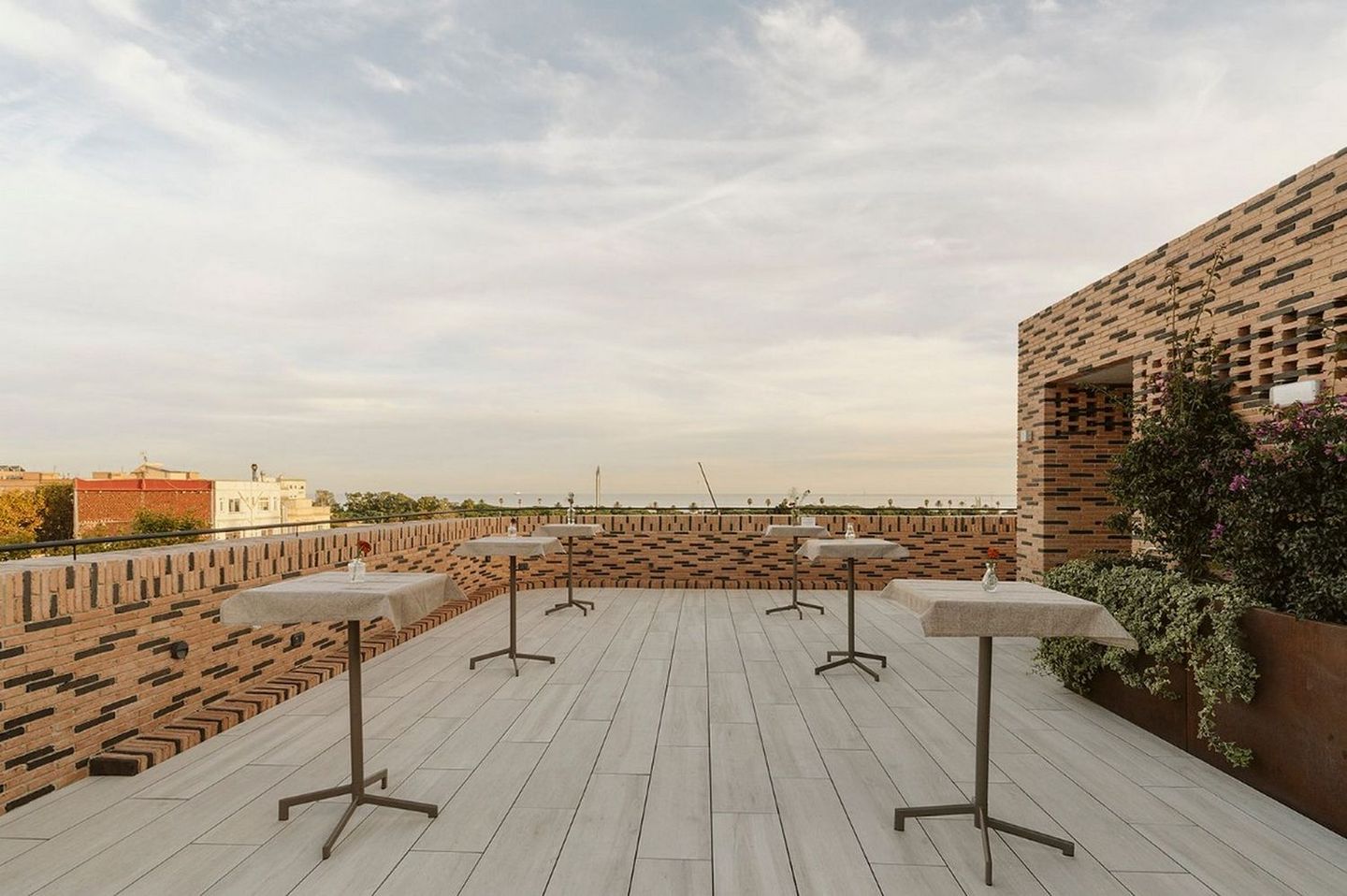 Empty terrace with small tables, brick walls and a cloudy sky