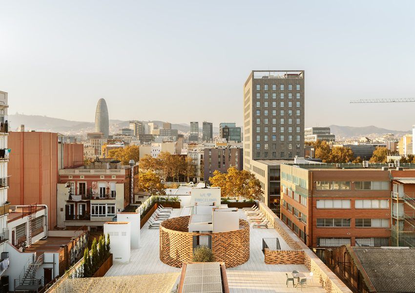 Azotea con tumbonas y paisaje urbano de edificios al fondo.