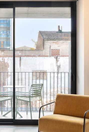 Mustard armchair by glass doors overlooking an outdoor table and chairs.