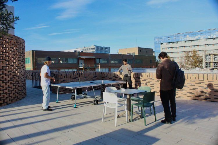 Personas trabajando y socializando en una terraza de coworking y coliving en Barcelona.