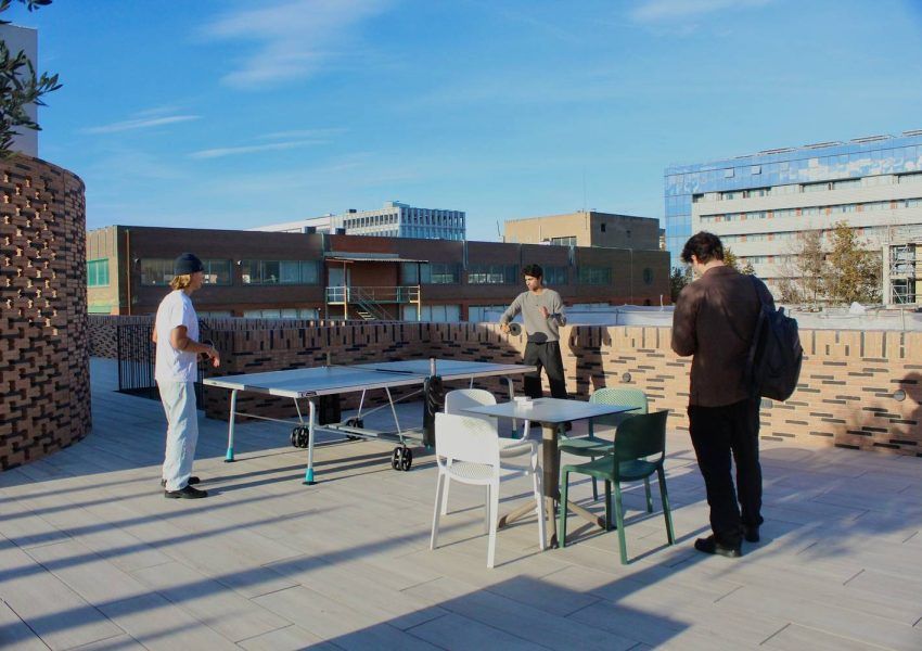 Personas trabajando y socializando en una terraza de coworking y coliving en Barcelona.